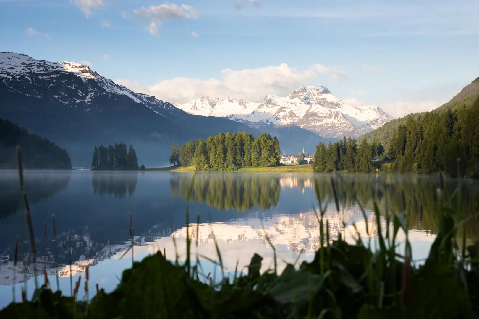 A picture of the Engadin valley with a lake on it.