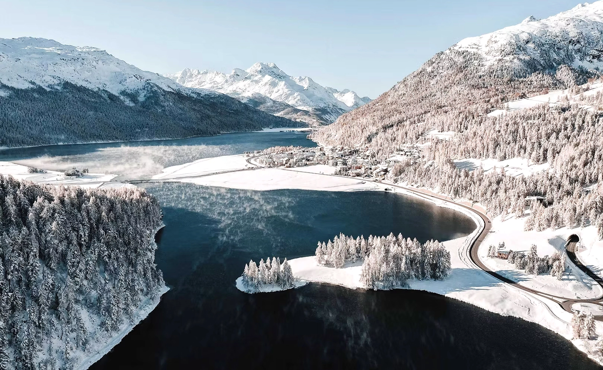 A picture of the Engadin valley with a lake on it, covered in snow.
